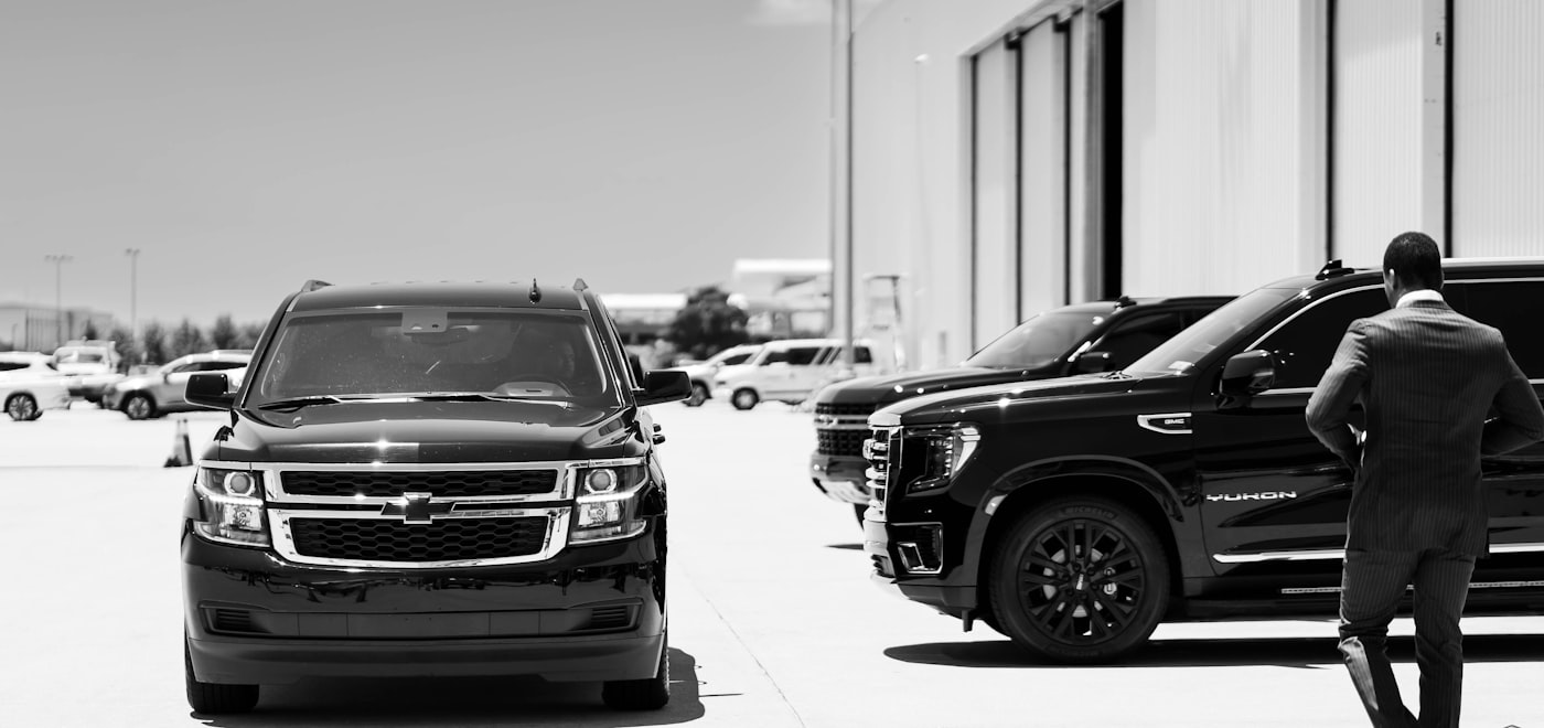 Professional chauffeur with black luxury SUVs — corporate transportation Long Island